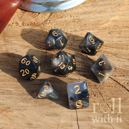 Set of polyhedral dice on a wooden surface with 'roll with it' branding.