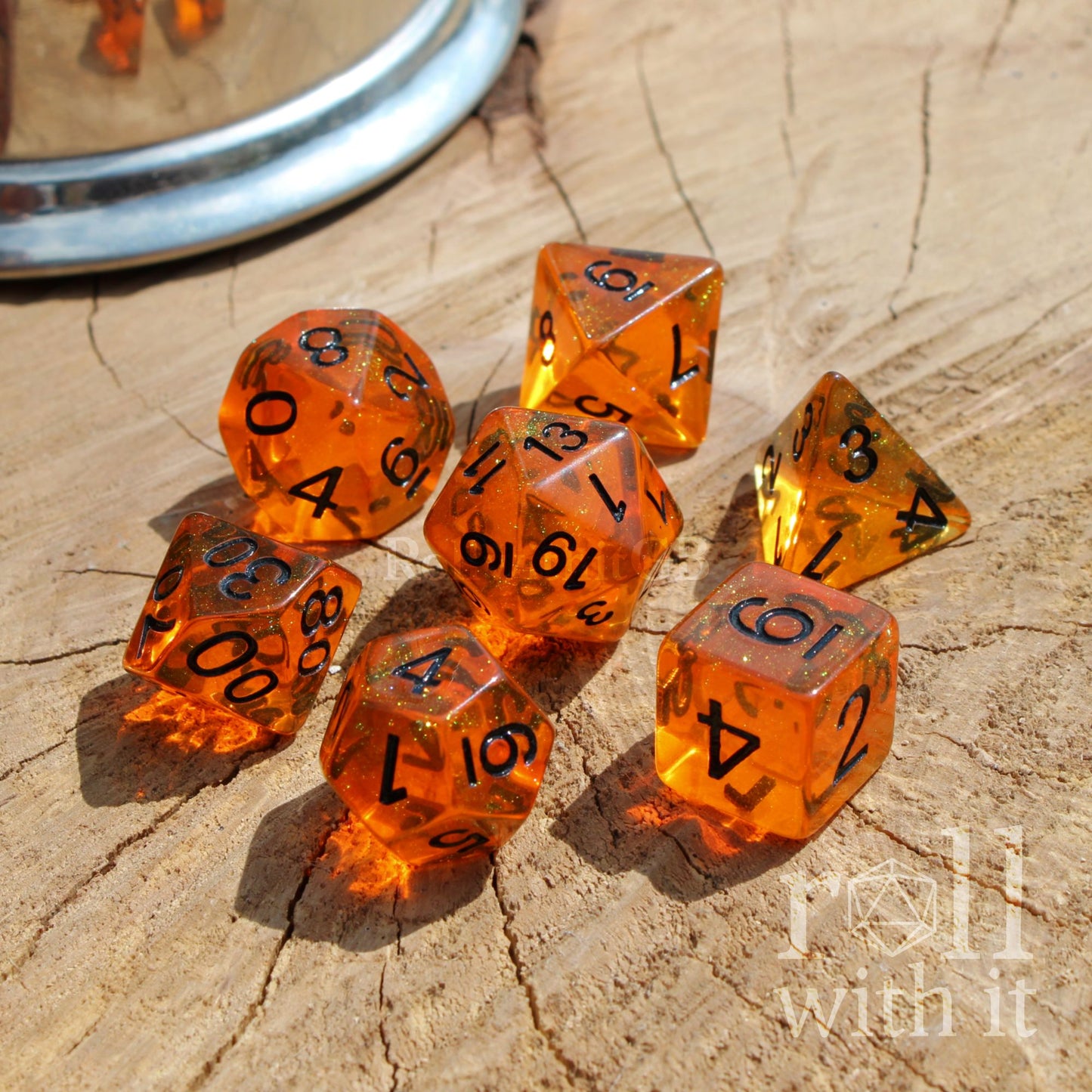 Bright clear orange dice set with black numbers on a wooden surface, featuring the 'roll with it' logo.