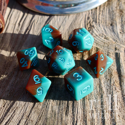 Set of shiny click clack teal and brown polyhedral dice on a wooden surface