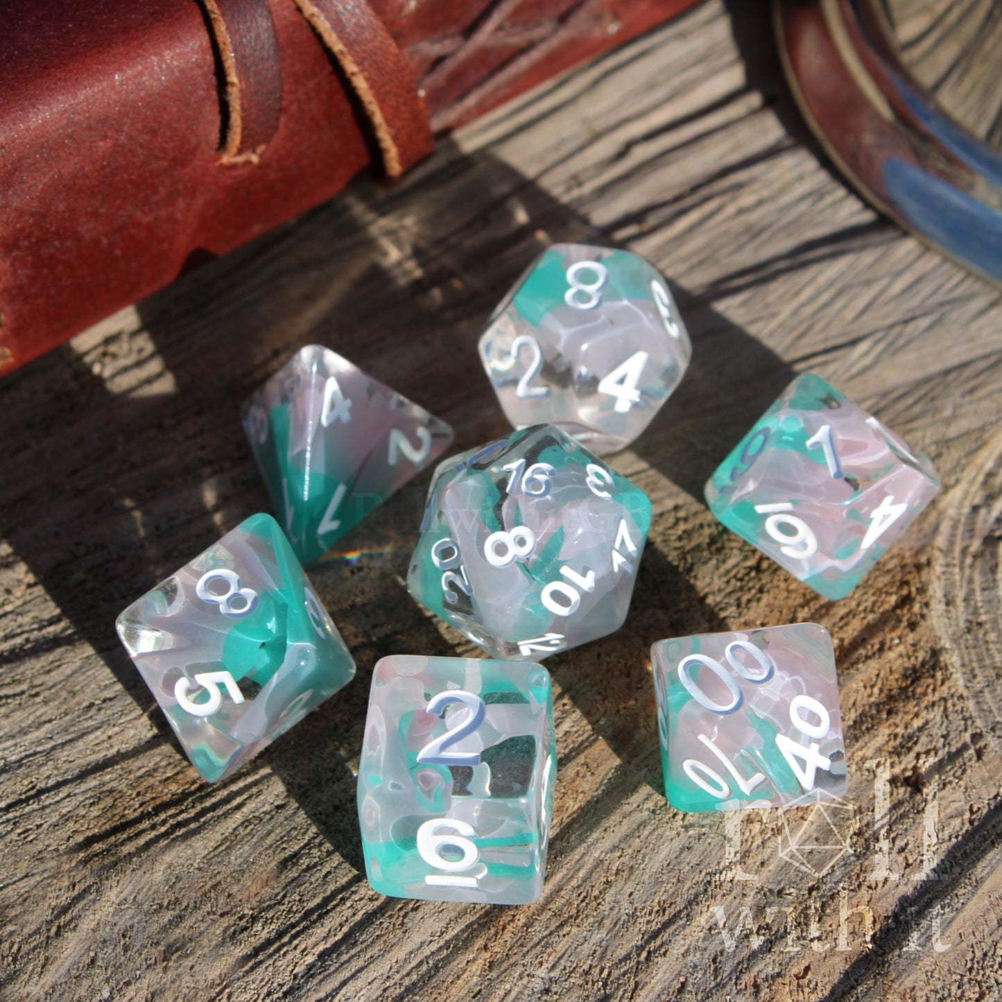 Set of teal and clear white swirled mixed polyhedral DND dice on a wooden surface