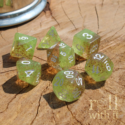 Set of green orange polyhedral dice on a wooden surface with 'roll with it' text.